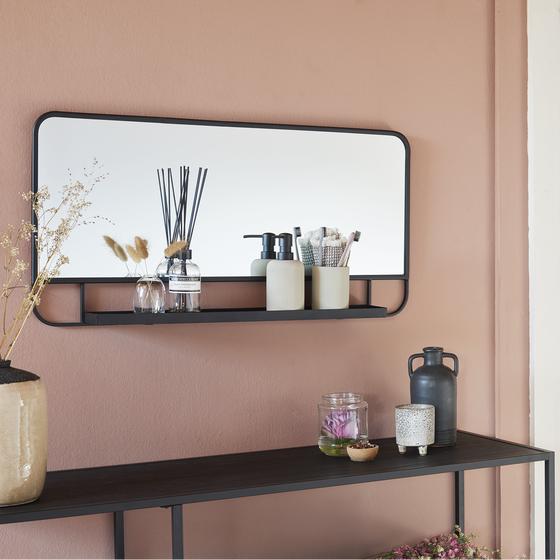 XL spiegel opgehangen aan de muur met decoratie erop