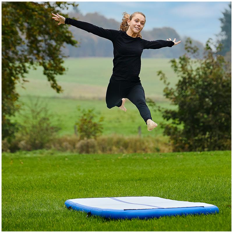Femme sautant au dessus du tapis de gym gonflable 