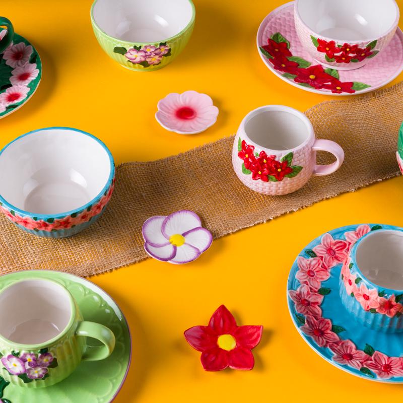 Coffret de tasses, bols et petites assiettes à fleurs sur une nappe colorée