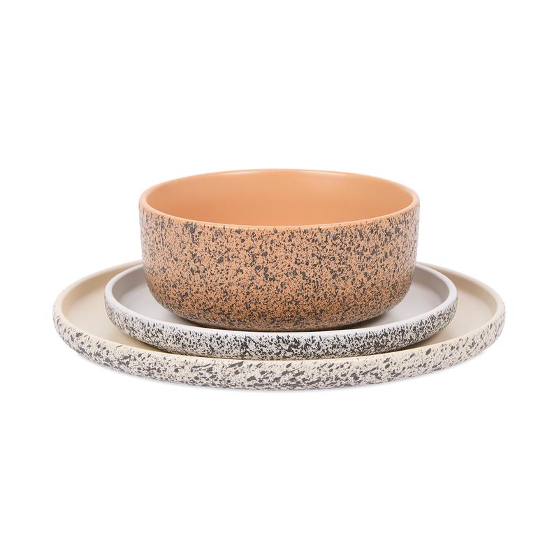 Petite assiette blanche, grande assiette beige et bol corail du service de table moucheté